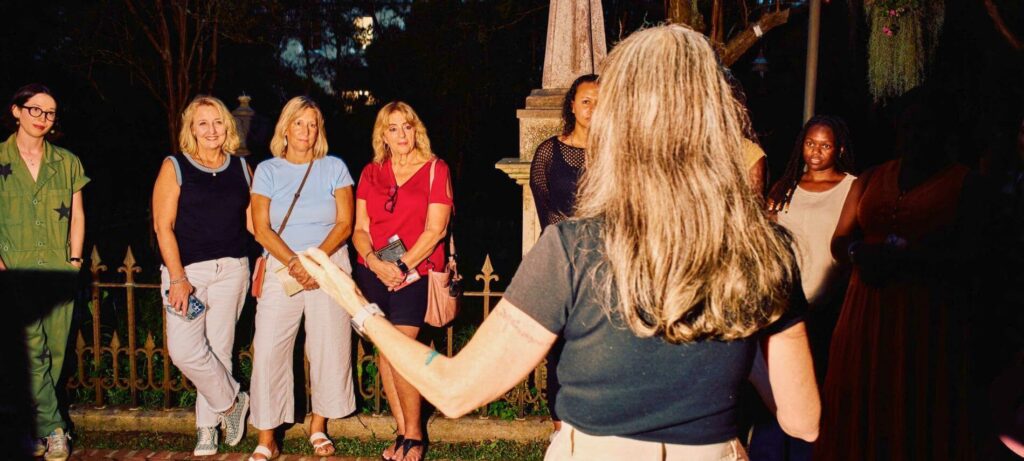 A tour guide shares stories with a group during an evening ghost tour in Charleston's historic district.